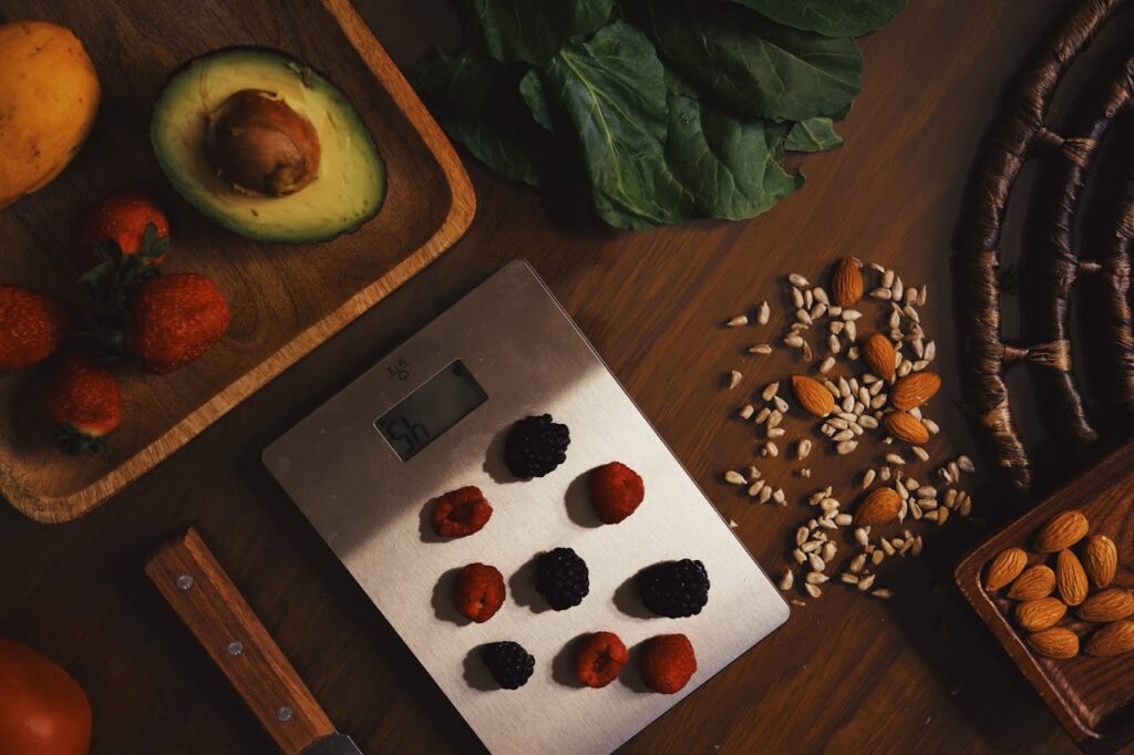 Blackcurrent and raspberries on a stainless steel scale, surrounded with aalmonds, seeds, vegetables and avocado.